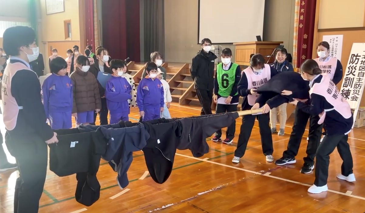 棒を持つ人の上着を両側から脱がせ、棒に通して担架に